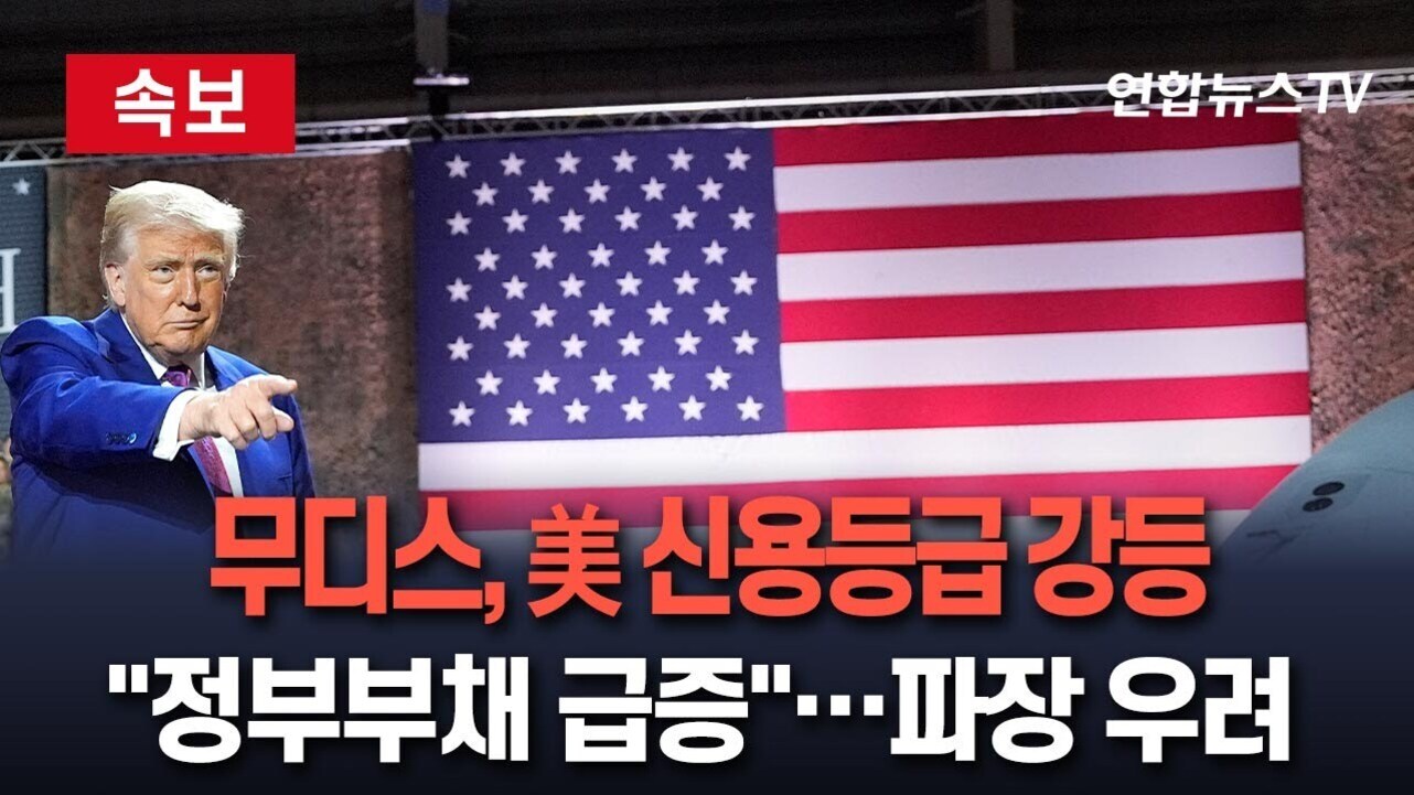 미국 국기 앞에서 한 남성이 손가락으로 가리키고 있으며, 화면에는 '속보', '무디스, 美 신용등급 강등', '정부부채 급증…파장 우려'라는 자막이 있다.