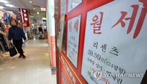 상가 내부 복도와 벽에 붙은 '월세' 임대 광고 안내문, 한 사람이 지나가고 있음.