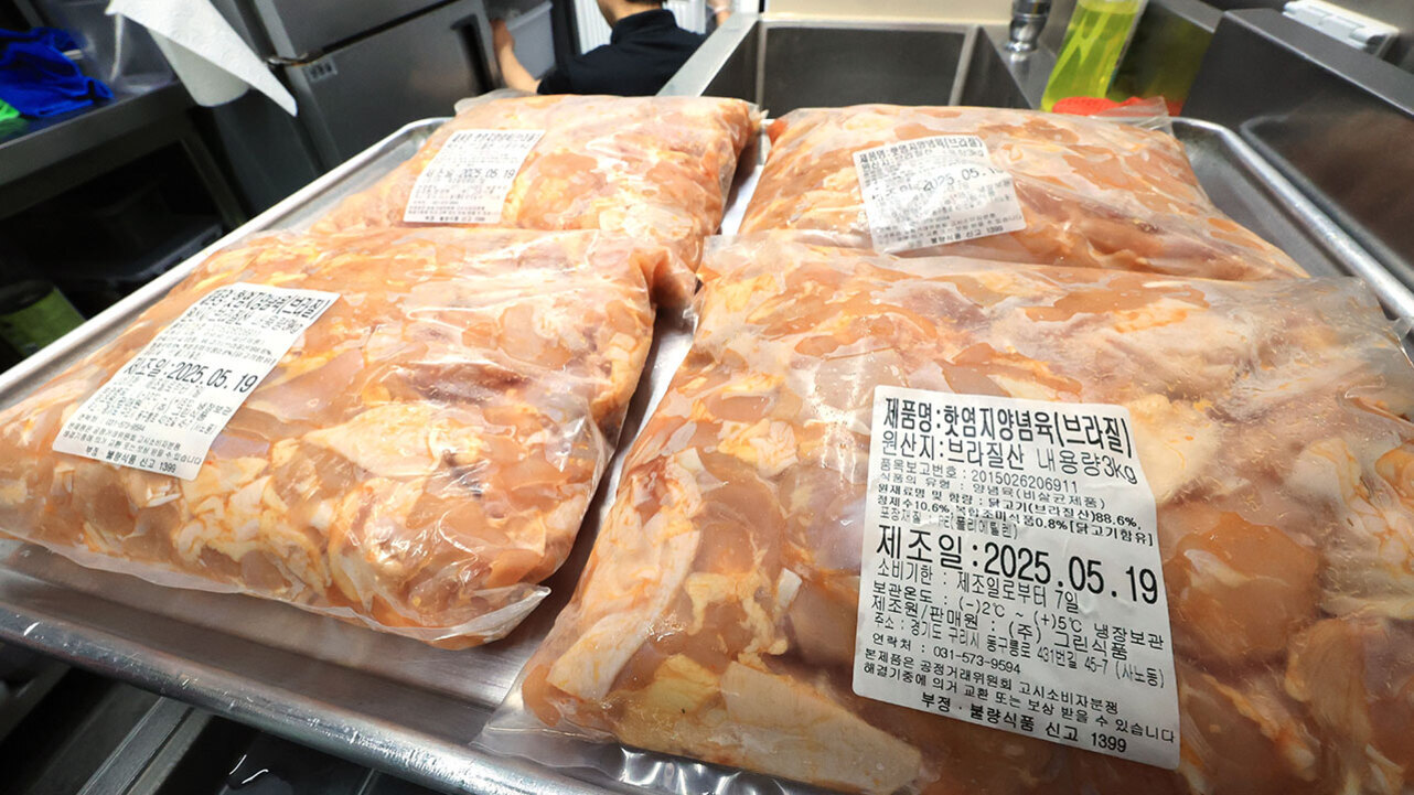 진공 포장된 닭고기(브라질산) 여러 팩이 스테인리스 쟁반 위에 놓여 있으며, 각 팩에는 제품명, 원산지, 제조일자 등의 정보가 적힌 라벨이 붙어 있다.